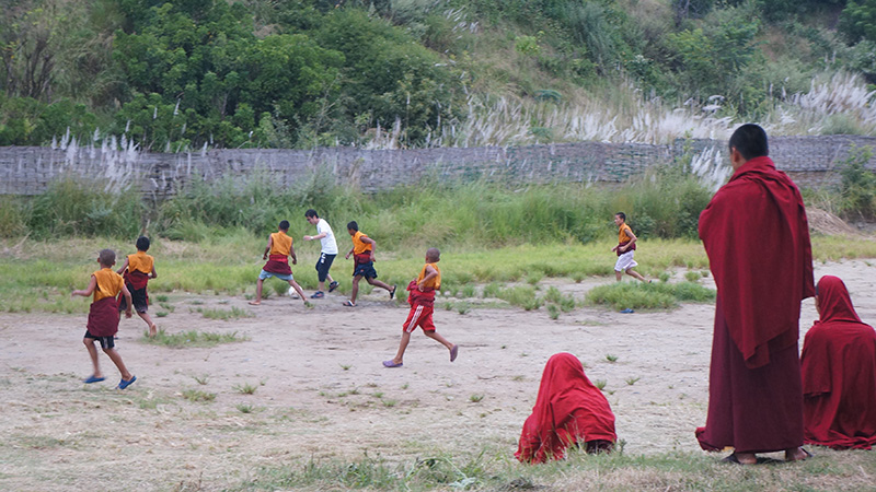 Kids have fun playing football in a simple "football field" in Bhutan.