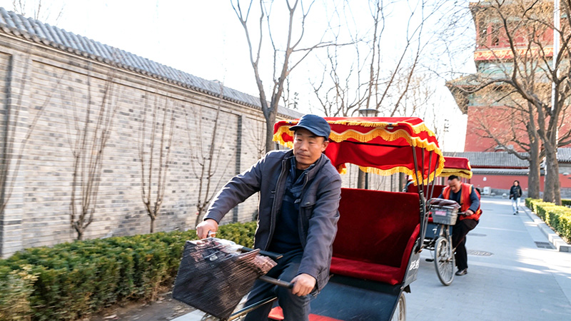 A rickshaw driver rides through a Beijing hutong