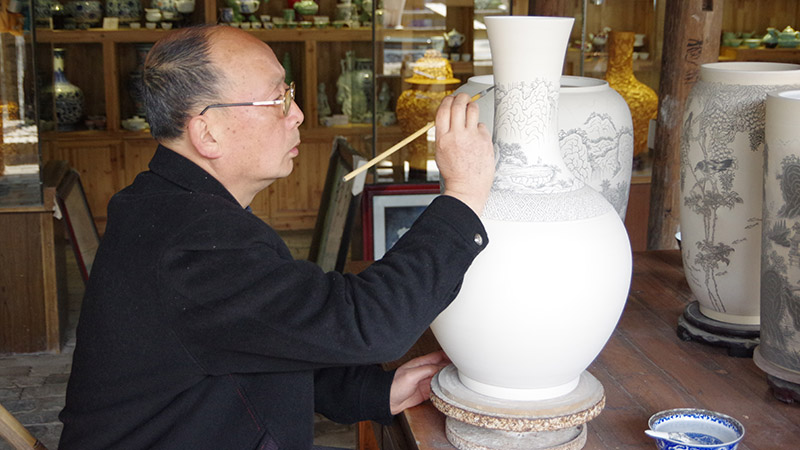 A master is painting a vase in Jingdezhen 